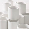 Hand-crafted white concrete vessels stacked  in an artistic manner on white background.