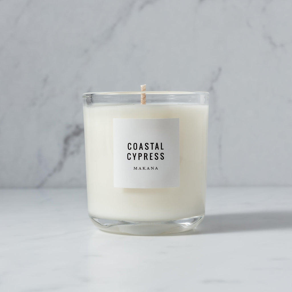 A Makana Coastal Cypress Classic Candle - NO PACKAGING with a coastal fragrance and the word coral cypress on it.