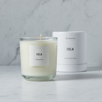 A Makana Isla - Classic Candle with a soft wood scent and the word "isla" on it.